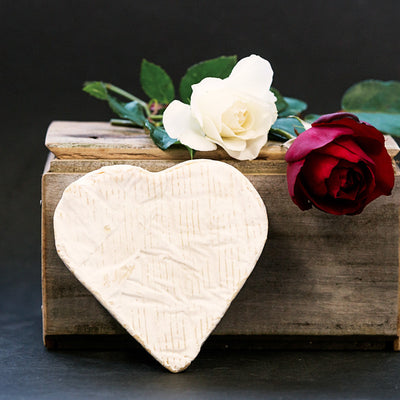 Wooden box with a heart-shaped object, white flower, and red rose on a dark background